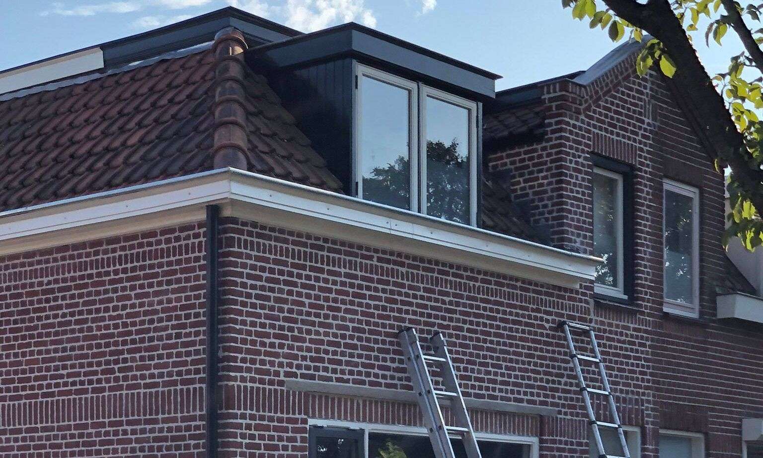Met de ladden een dakgoot inspecteren in Haarlem